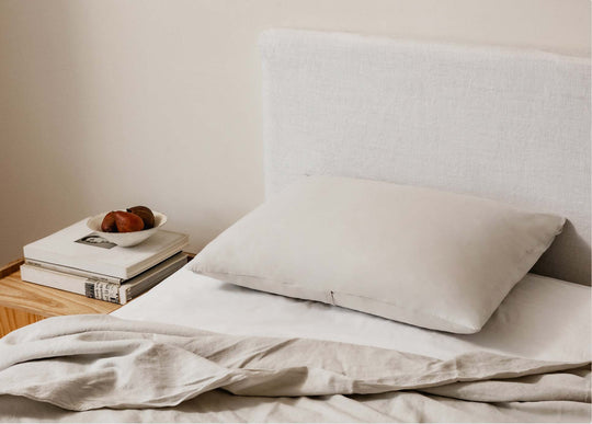Aesthetic pillow in linen sheets on top of an upholstered bed with neutral tones